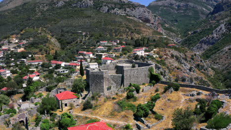 rotating aerial 4k shot of the stari bar fortress in montenegro with a mountain gorge in the background and a small city at its base