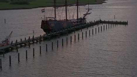 Drone-shot-of-Sailing-vessel-Soeverein-docked-in-the-harbour-of-Makkum-with-sunset,-aerial