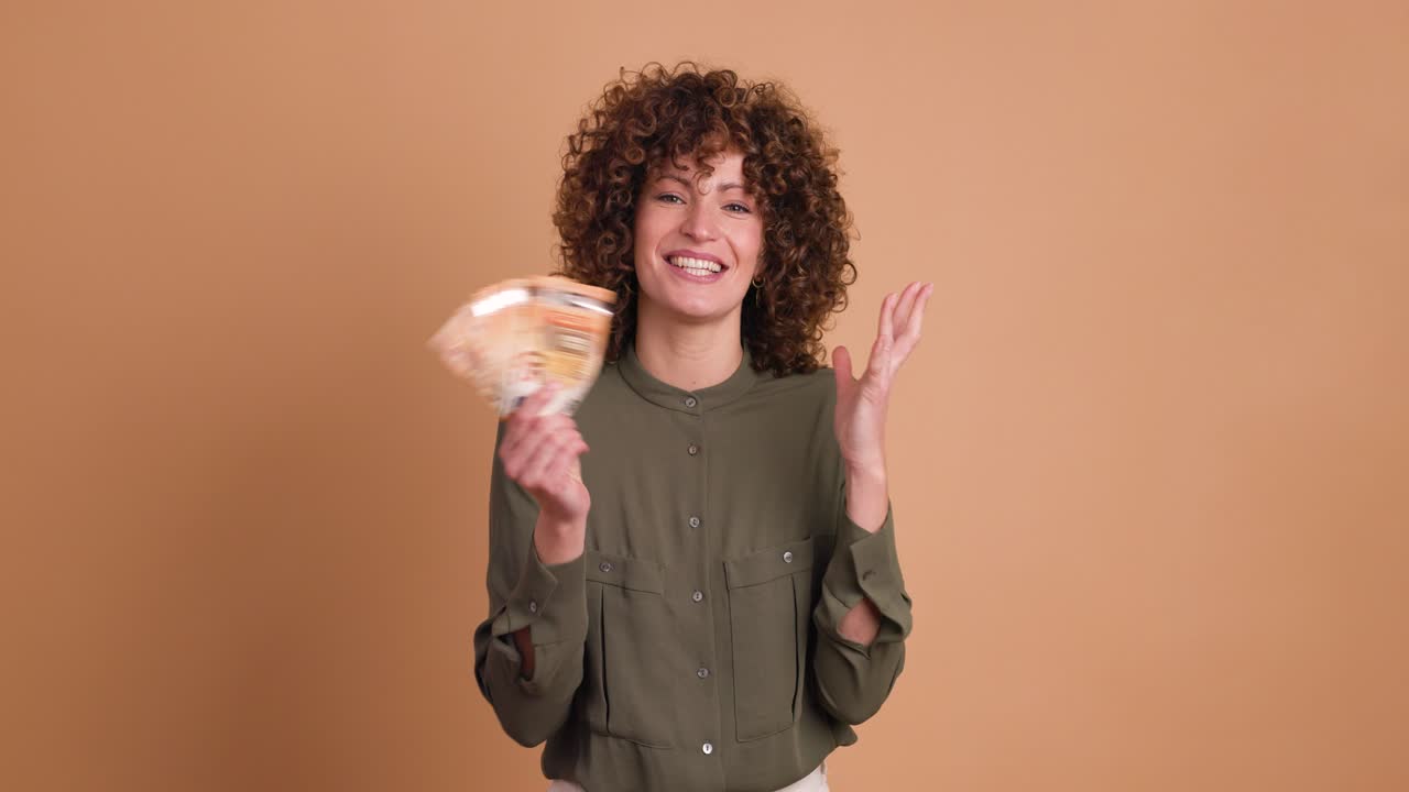 Cheerful woman showing Euro banknotes in beige studio
