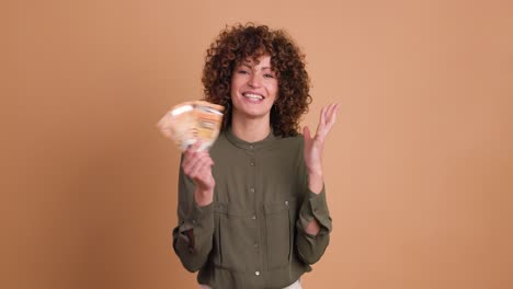 cheerful woman showing euro banknotes in beige studio