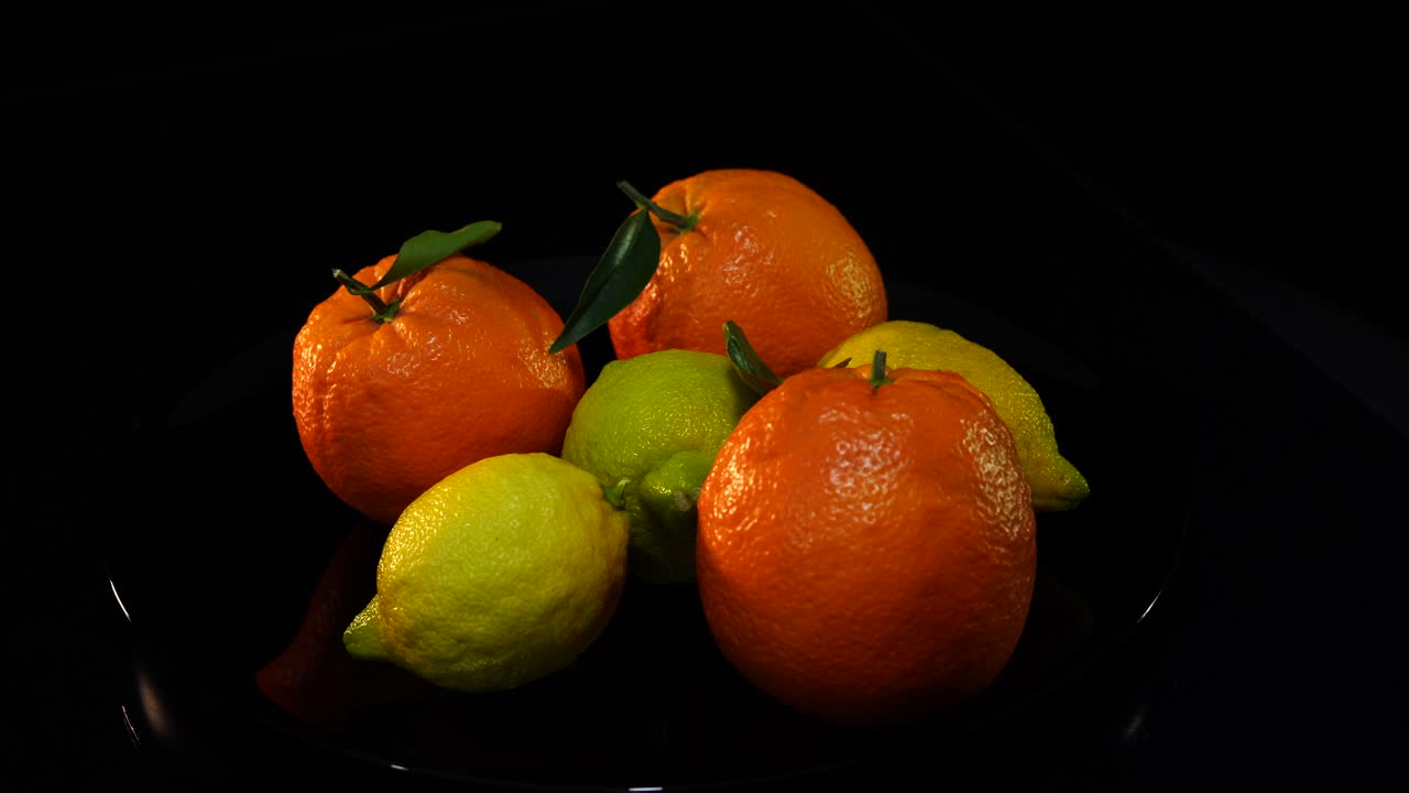 Arance e limoni su sfondo nero, agrumi ricchi di vitamine naturali.