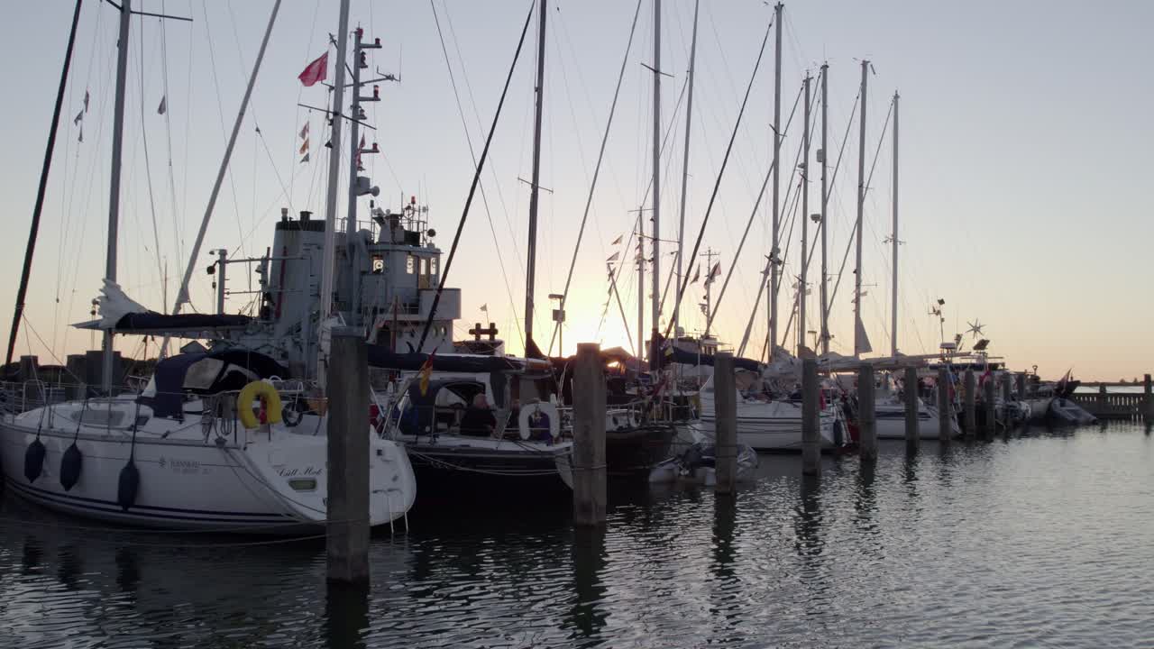 Veduta aerea di una scena portuale al tramonto con yacht e persone sull'IJsselmeer a Makkum, Paesi Bassi, con una splendida illuminazione del tramonto, atmosfera calma, filmato drone di alta qualità che cattura momenti sereni.