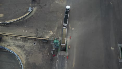 worker in industrial factory working with grain cargo truck at unloading process