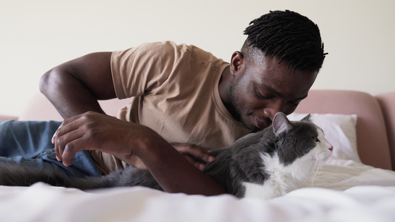Pet owner with his cat on bed