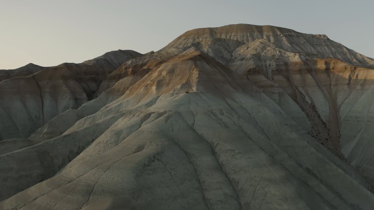 impresionantes tomas de drones capturando majestuosas cadenas montañosas rocosas de américa del sur, bañadas en el cálido resplandor de una puesta de sol contra un cielo despejado que mejora el paisaje dramático