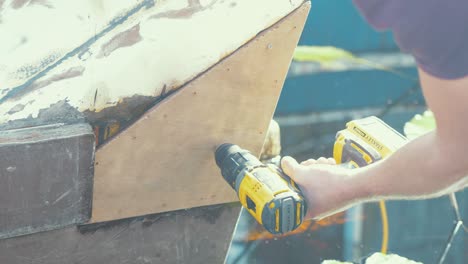 pre-perforación de una reparación de madera contrachapada en la popa de un barco de tablas