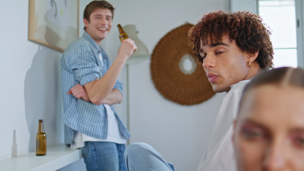 Modern guy drinking beer living room party. Happy man hanging out with friends