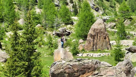 man standing on rock with drone remote controller surrounded by nature of val masino in valtellina, italy