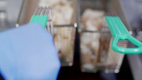 Potato-wedges-in-deep-fryer-baskets-put-into-oil,-rack-focus-close-up