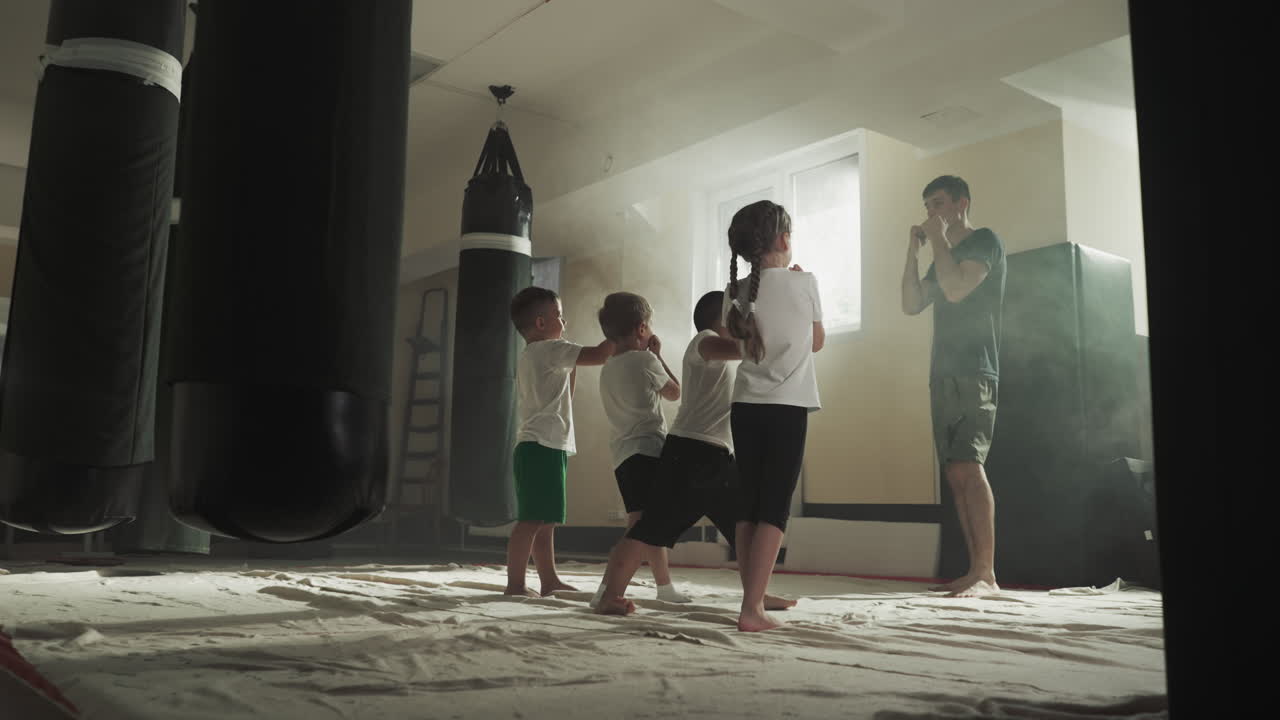 아이들은 체육관에서 트레이너를 모방하는 손으로 공기를 때립니다. 활동적인 어린 아이들은 스포츠 학교에서 무술 마스터와 함께 공격을 훈련시니다. 느린 동작. 건강한 삶.