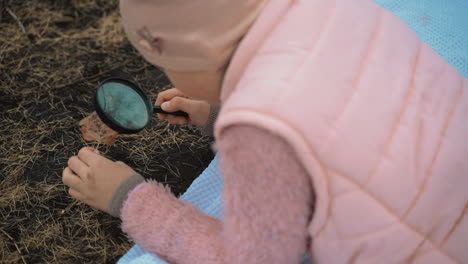 little girl looking through a magnifying glass in nature