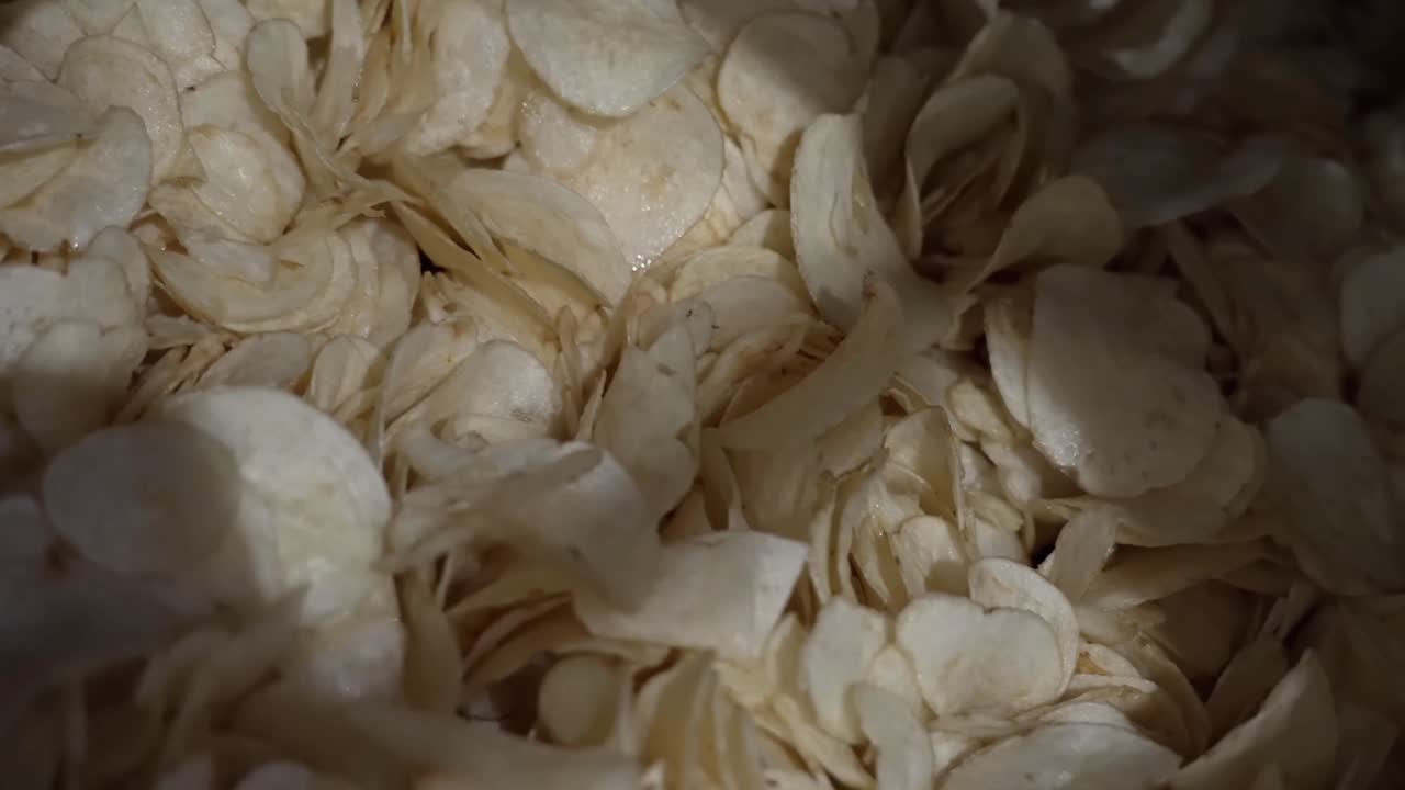 Close up shot process of frying potato chips on a factory conveyor