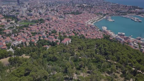 Flying-dynamically-over-the-trees,-towards-the-port-of-Split,-Croatia