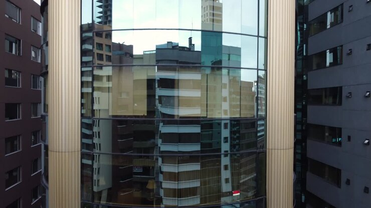edifício com painéis de vidro com o reflexo de outros edifícios da cidade, estrutura e arquitetura moderna