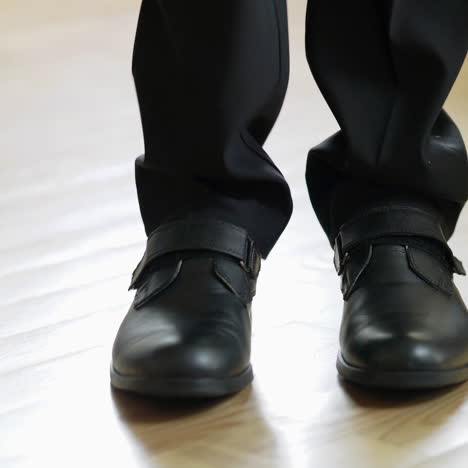male's legs wearing elegant shoes come into the room, stand for a while and go away. a pair of stylish shoes on a man in black suit on the floor inside