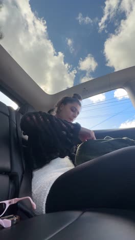 woman sitting in car with sunroof view of sky