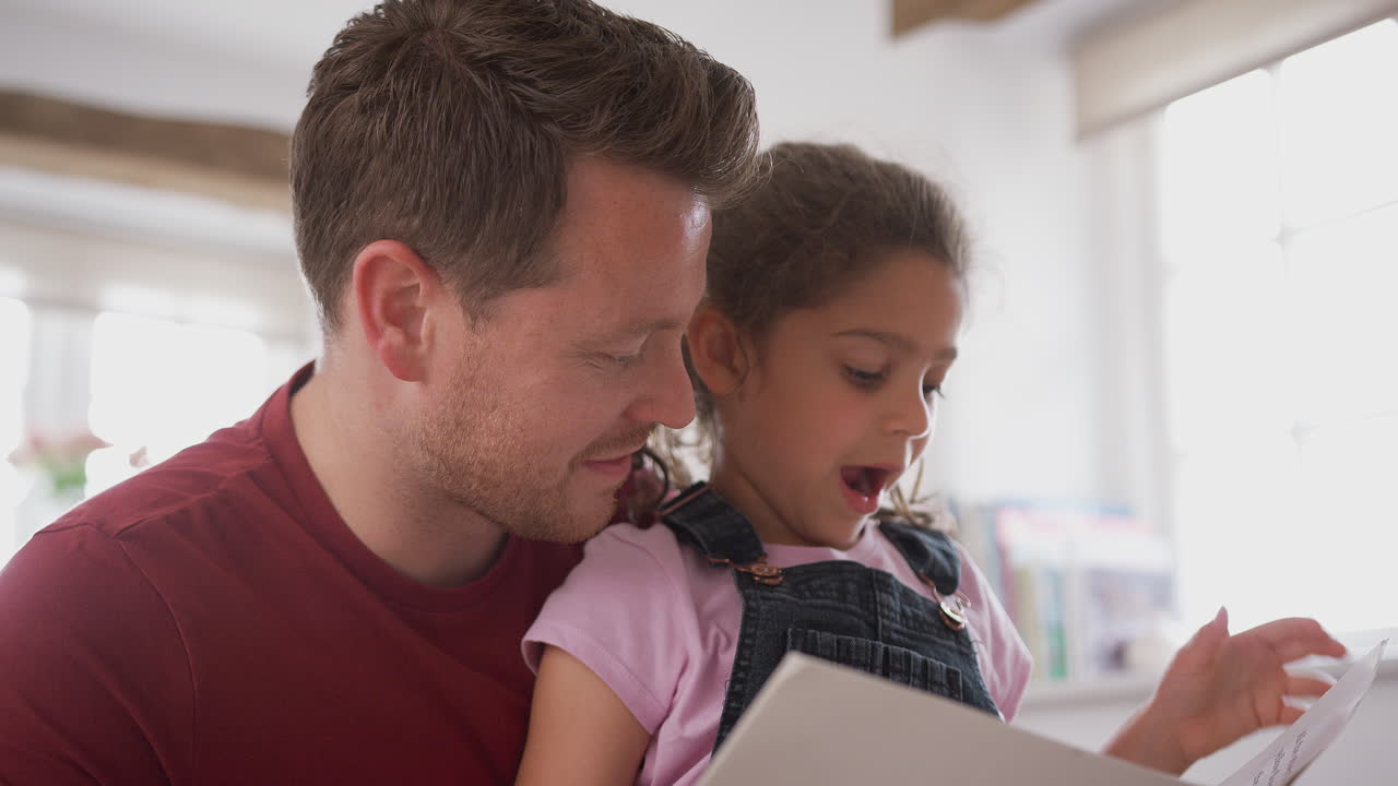 padre e hija en el dormitorio leyendo un libro juntos