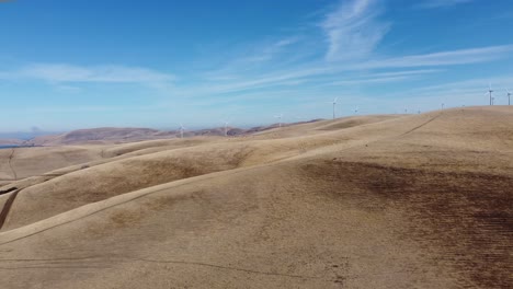 traveling drone footage moving in on energy producing windmills in the rolling hills of california