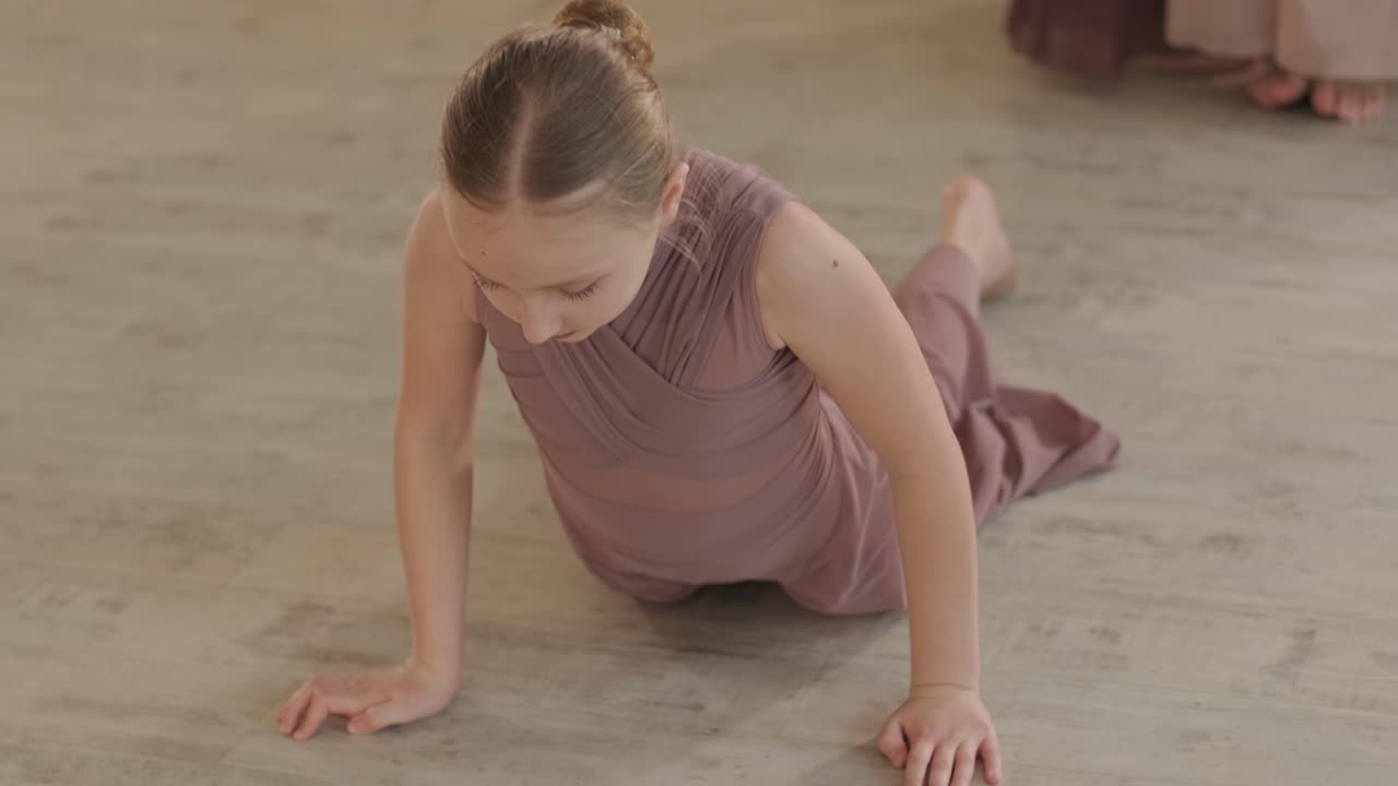 un grupo de jóvenes estudiantes de ballet con ropa de baile negra practicando posiciones en un amplio estudio de ballet con pisos de madera y barras montadas en la pared. expresiones enfocadas y movimientos sincronizados.