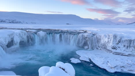 Wasser-Stürzt-Kurz-Nach-Sonnenaufgang-Den-Weiten-Godafoss-fall-In-Eine-Verschneite-Landschaft