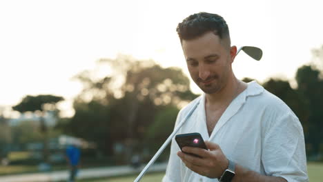 man using phone on golf course