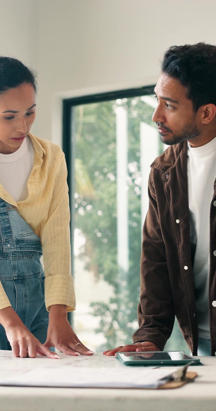 Due professionisti che collaborano su planimetrie architettoniche in un ufficio moderno