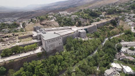 Impressive-Gjirokaster-Castle-overlooking-the-cityscape,-Aerial-view,-Albania