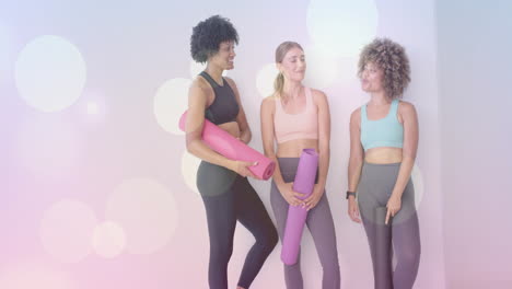 tres mujeres sosteniendo esteras de yoga, de pie y hablando, con animación de luces bokeh