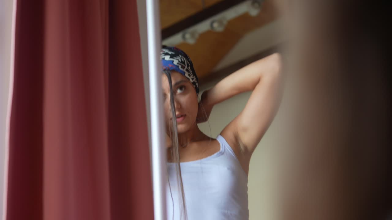 Woman adjusting her hijab in front of a mirror