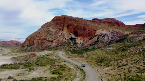 Toma-Aérea-De-Un-Camión-De-Expedición,-Overlander-En-Un-Camino-Polvoriento-Paisaje-Salvaje-De-Montaña-Ocre,-Ruta-41-Argentina