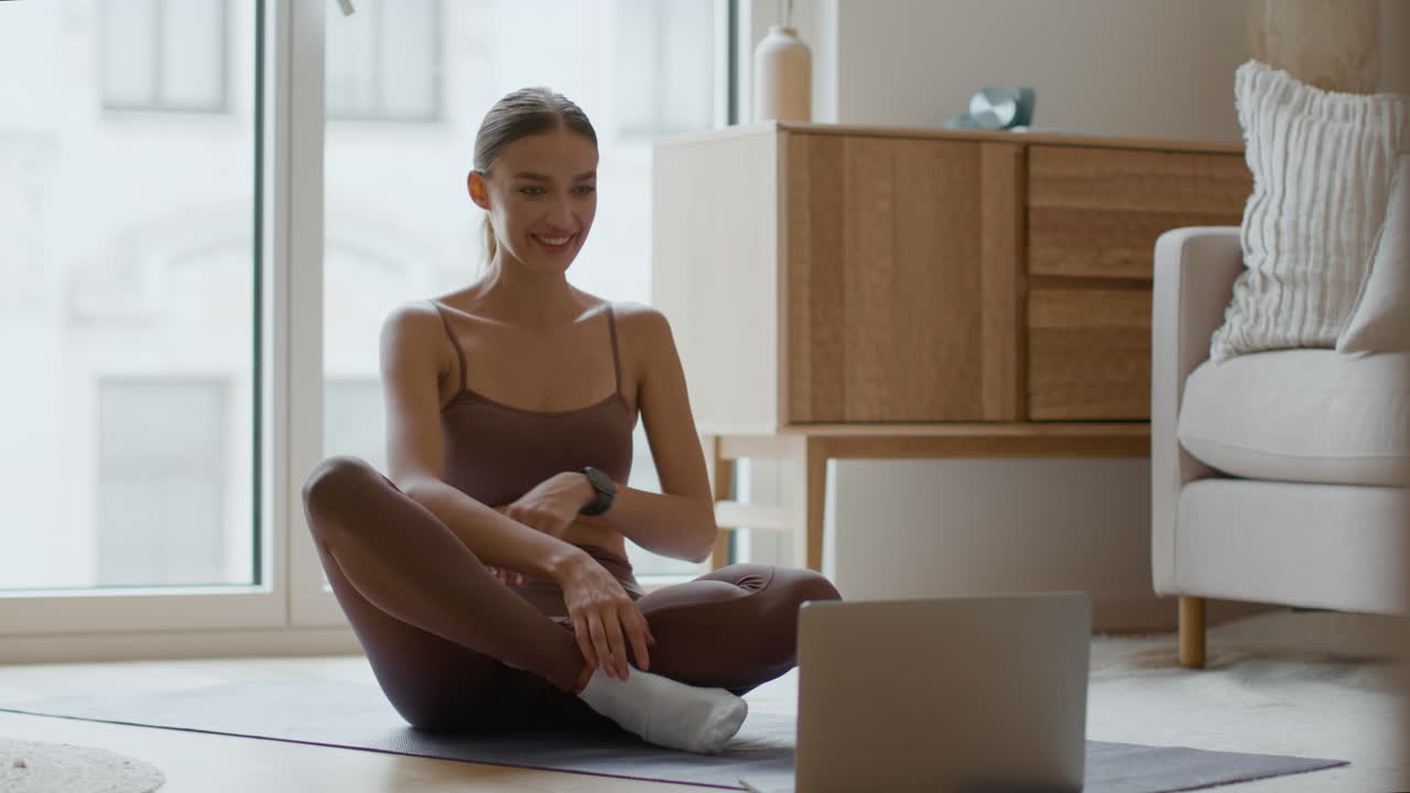 Woman doing yoga at home via online video call