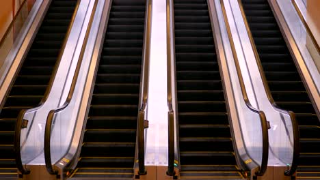 una escalera mecánica con escalones negros, que asciende a una luz brillante, flanqueada por barandillas metálicas reflectantes en un entorno tranquilo y vacío