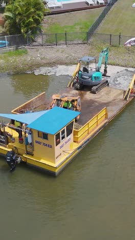 aerial view of a barge with a crane working in a canal near luxury homes, showcasing urban construction