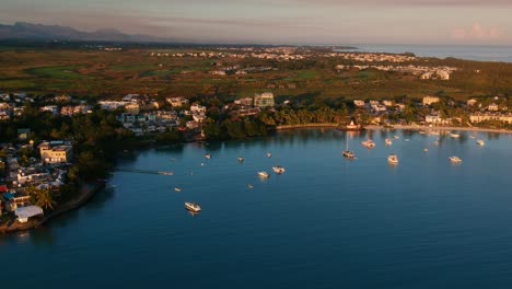 Panorámica-Aérea-De-Gran-Bahía,-Con-Barcos-Anclados,-Casas,-Tierra-Verde-Y-El-Océano-Y-Las-Montañas-En-El-Fondo