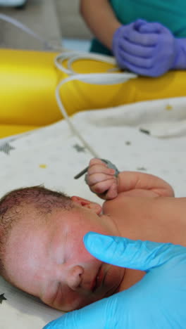 unrecognized neonatologist touching newborn baby's face. the child doesn't like the gloved hand's touch. close up. vertical video