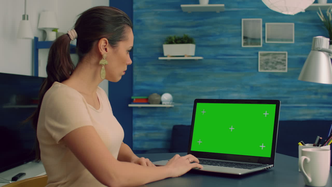 mujer caucásica escribiendo en una computadora portátil con una maqueta de pantalla verde con pantalla de teclas cromáticas