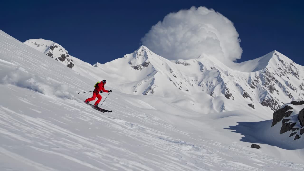 Uno sciatore in rosso scende lungo un pendio innevato, ripreso da una ripresa ad angolo basso, enfatizzando la velocità