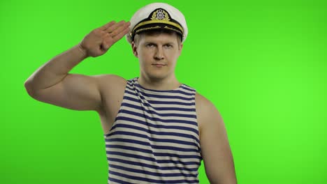 young sailor man salutes with hand to camera. seaman guy in sailor's vest