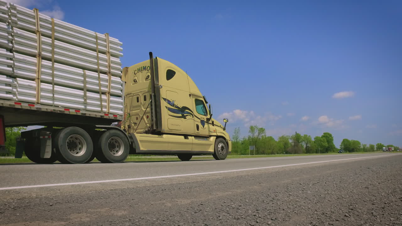 Large double length transport truck carrying pipes down a highway