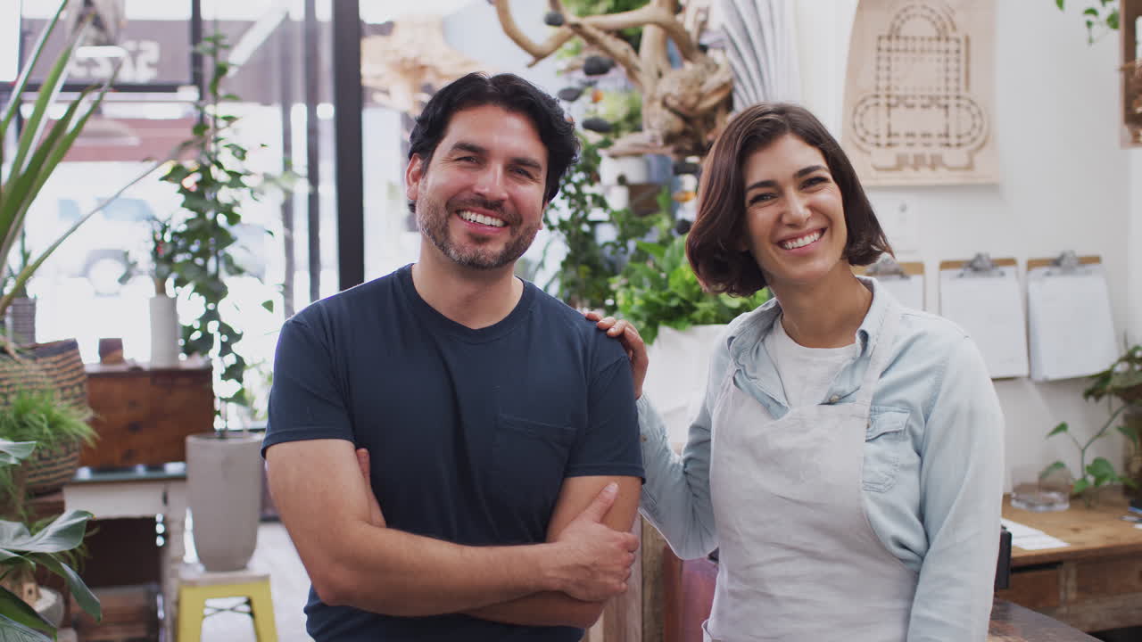 retrato de hombres y mujeres sonrientes asistentes de ventas de pie junto al mostrador de ventas de la tienda de flores