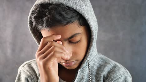 sad man in hood cover face with hands isolated in black