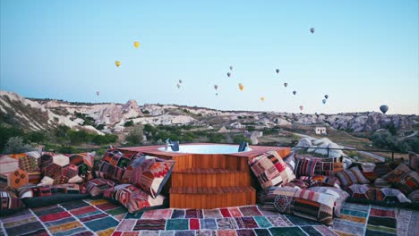 The-beautiful-and-charming-terrace-with-colorful-hand-made-carpets-and-hot-air-balloons-flying-over-Red-valley-in-background