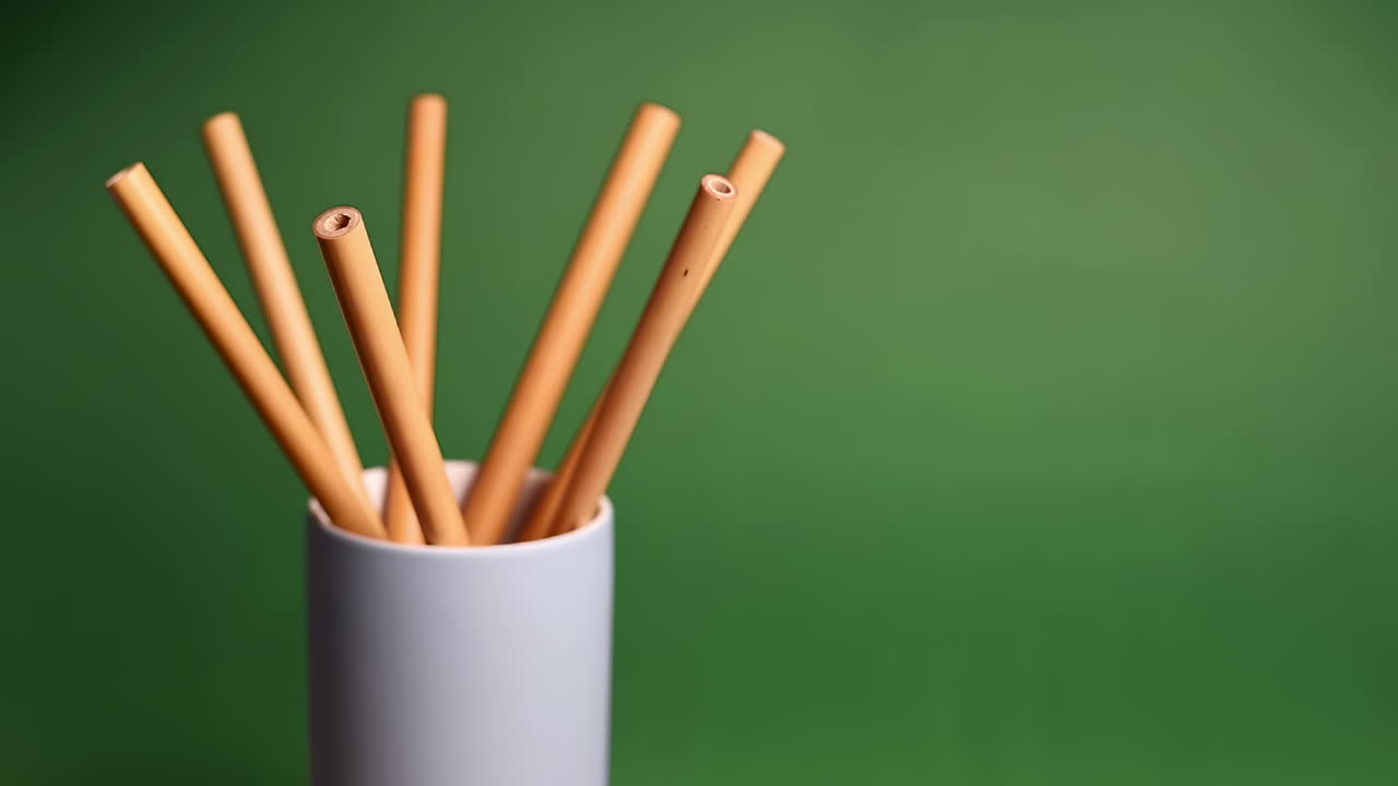 Bamboo straw in a glass demonstrating with a green background