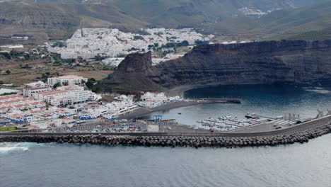 toma aerea sobre el puerto de agaete apreciando los barcos en el muelle y las casas