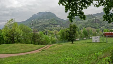 cloudy sky over lush green landscape backdropped by majestic mountain in bolzano, south tyrol, italy. panning shot