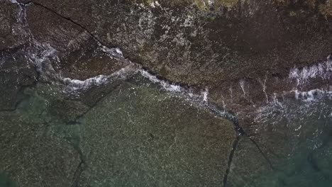 hd drone footage capturing stunning clear ocean water crashing against rugged rocks on the shores of oahu. showcasing the power and beauty of hawaii’s coastline in a breathtaking aerial view.