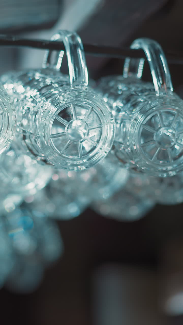 Clean glass mugs for beer hang on metal rack in empty pub closeup. Shiny glassware prepared for guests serving in bar. Public place for alcohol drinking