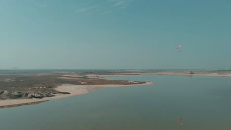 Vista-Aérea-Del-Parapente-Motorizado-Que-Vuela-Sobre-El-Lago-Salado-En-La-Distancia