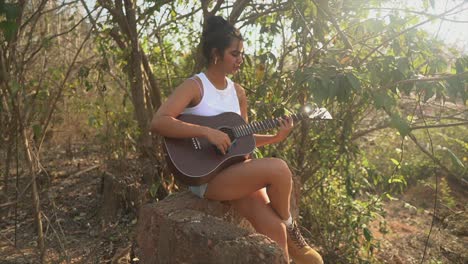 attractive girl playing her guitar in a sunny outdoor spot