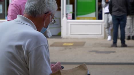 Over-the-Shoulder-Shot-of-Elderly-Man-In-Face-Mask-Sitting-On-Bench-02